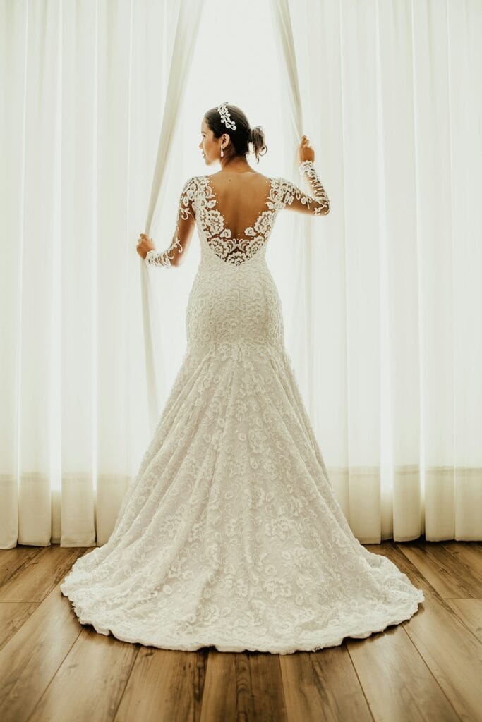 Bride in a lace wedding gown by a window