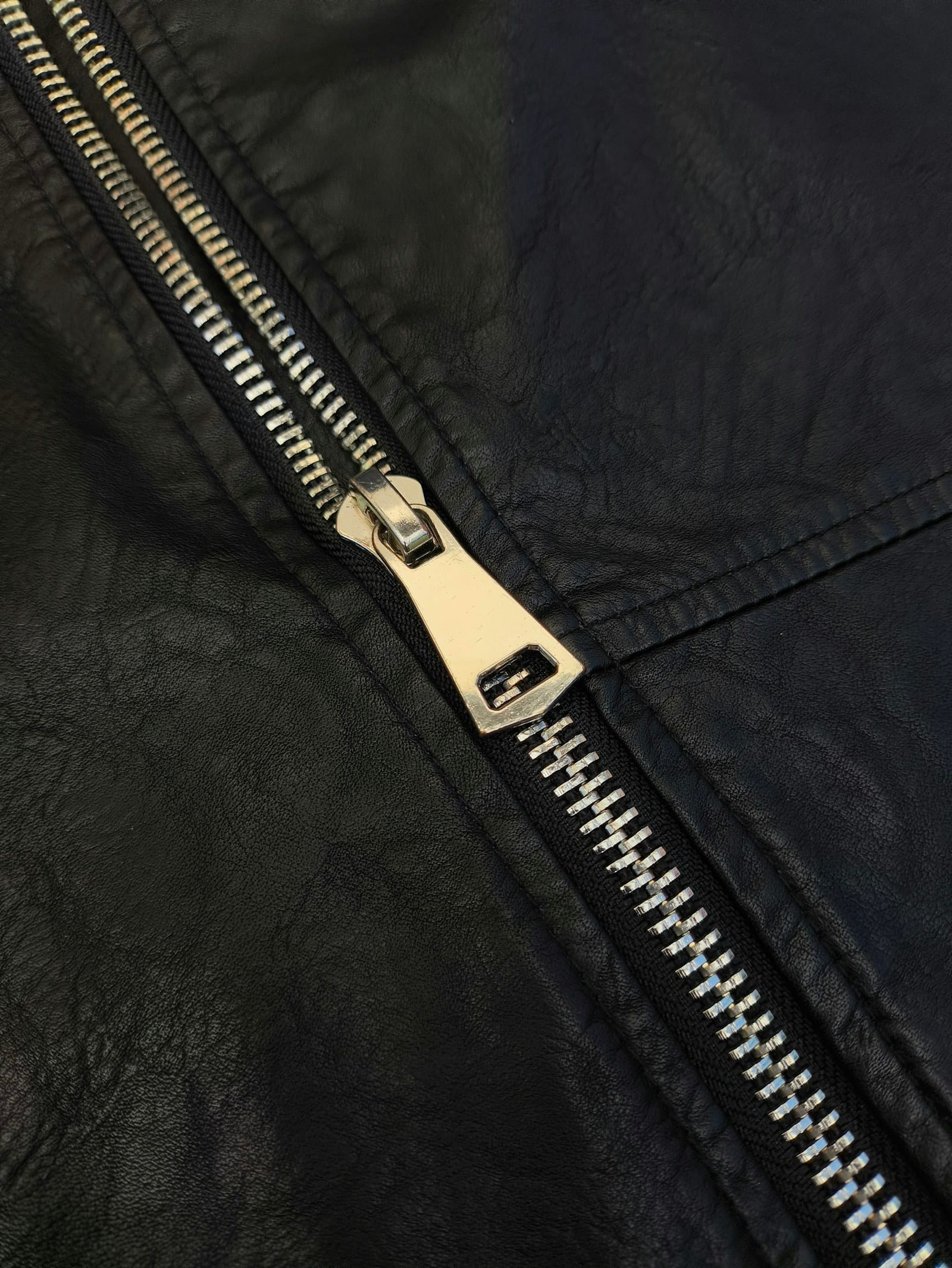 Zip, topstitching and grain on a black leather jacket, construction detail